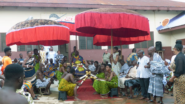 The courtyard of the king with bright red umbrellas covering him and his court from the sun.