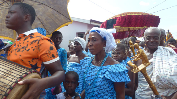 Village members procession in colorful clothing.